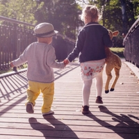 Kids holding hands and running across a bridge.